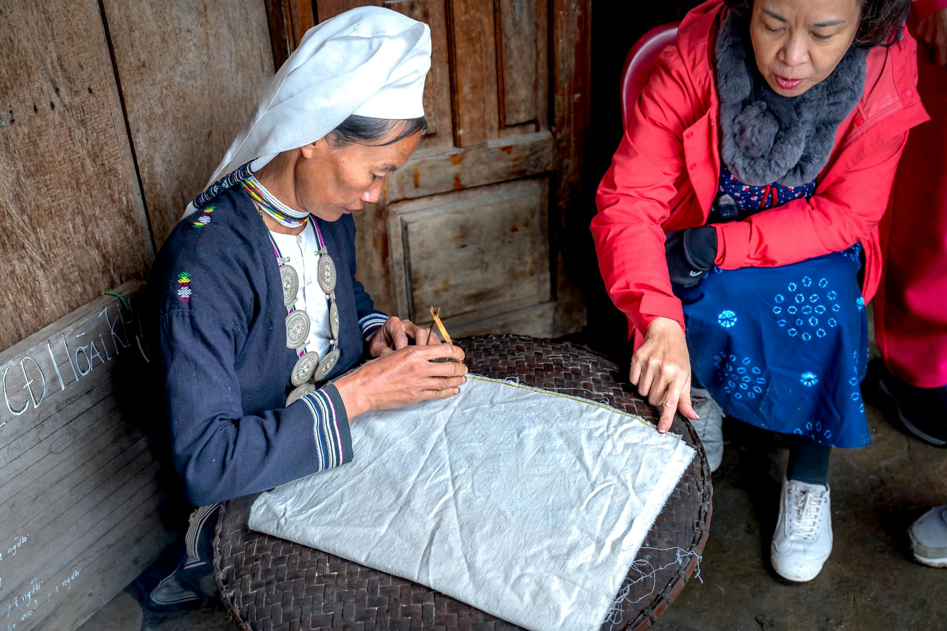 Starsza Indonezyjka uczy się tradycyjnego tkania materiału