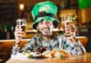 Co zjeść w Irlandii: przewodnik po tradycyjnej kuchni, pubowych klasykach i nowoczesnych bistro Mężczyzna w zielonym kapeluszu leprechauna z piwami w irlandzkim pubie