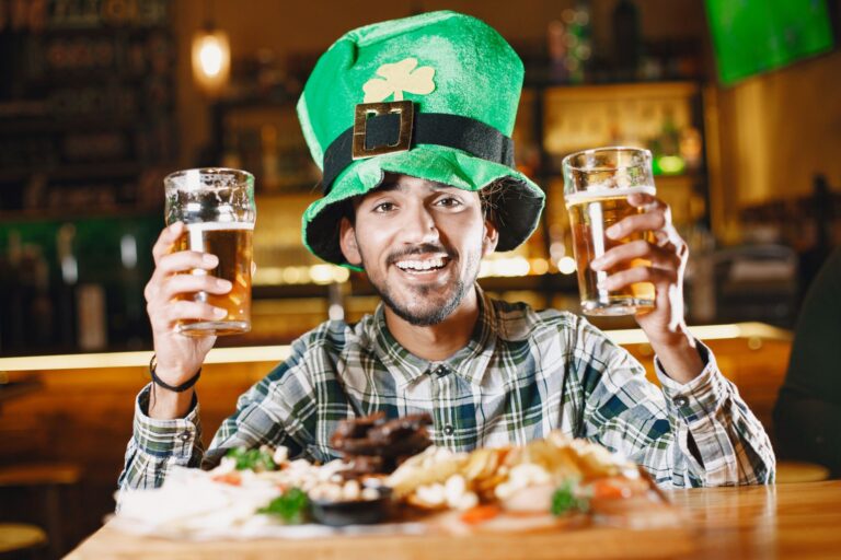 Mężczyzna w zielonym kapeluszu leprechauna z piwami w irlandzkim pubie