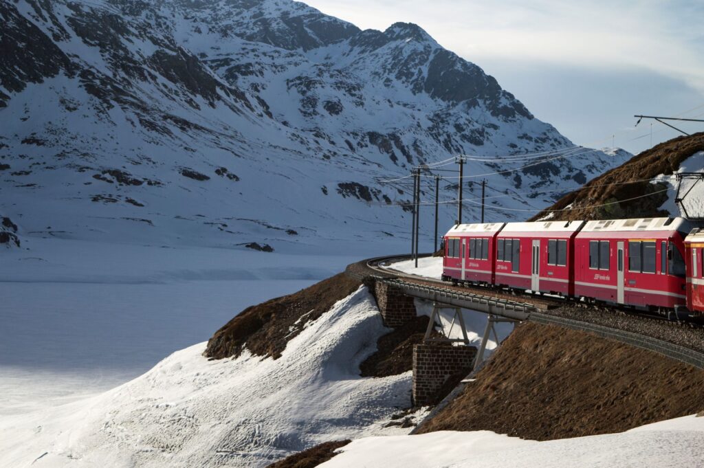 Czerwony pociąg Bernina Express wśród ośnieżonych Alp Szwajcarskich zimą